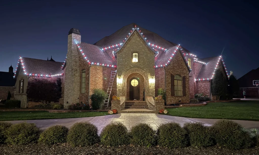 Luxury brick home with professional Christmas lights installed along the roofline and entryway